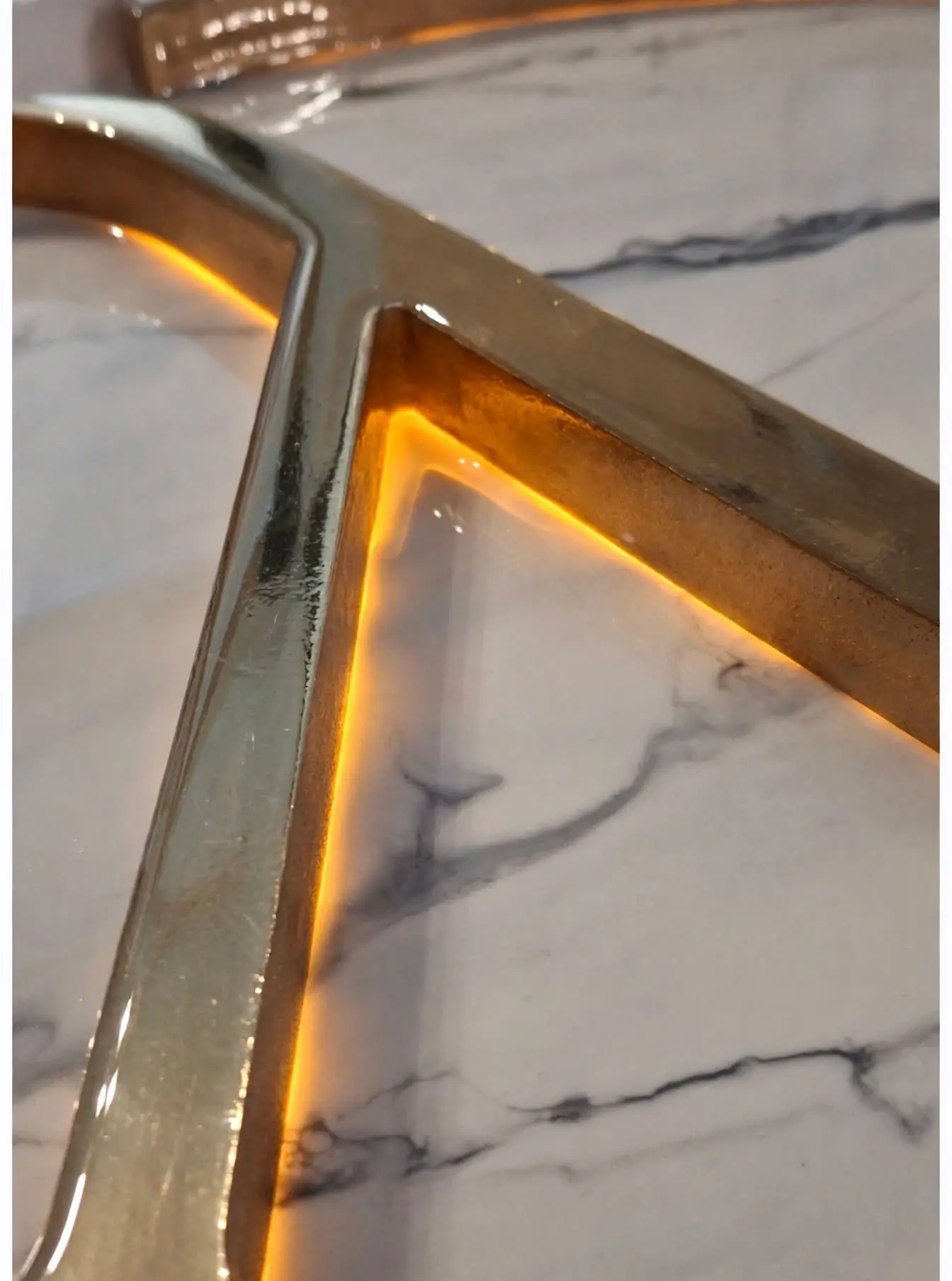 Mesa de madera con logo personalizable retroiluminado con LED - detalle macro letra N en latón dorado sobre resina efecto mármol blanco