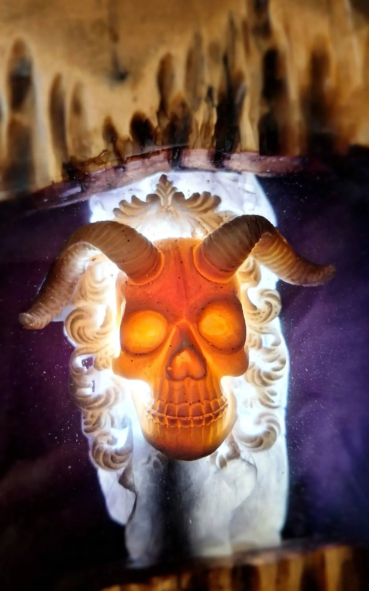 Detalle de lámpara de pared horror artesanal con calavera con cuernos iluminada en resina morada y madera, 25x50 cm personalizable por encargo
