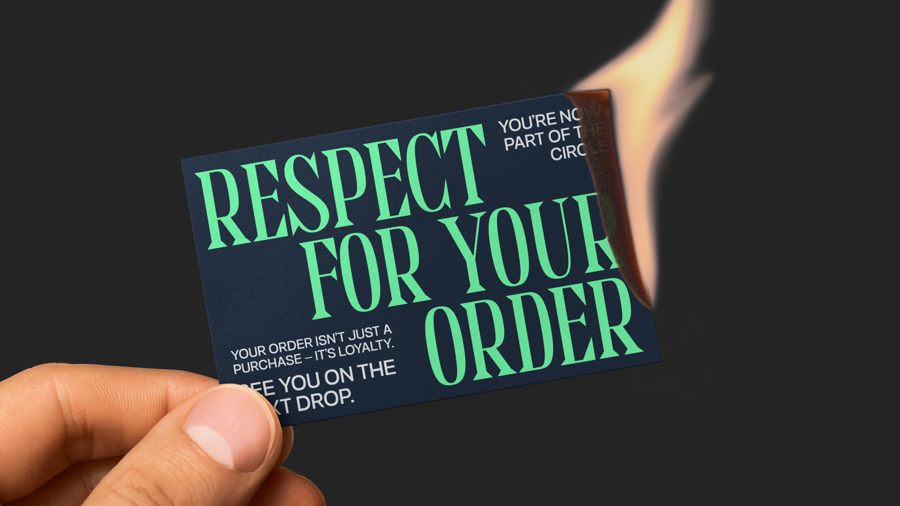 A hand holding a dark card with the text 'Respect for your order' partially burning on the top right corner.