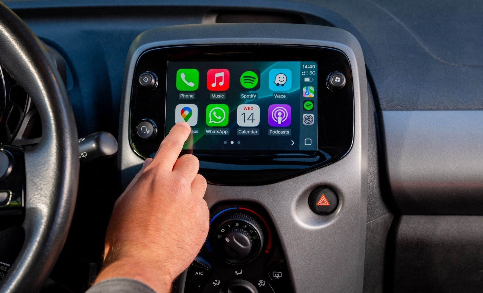 Hand pointing at car dashboard screen with Apple CarPlay