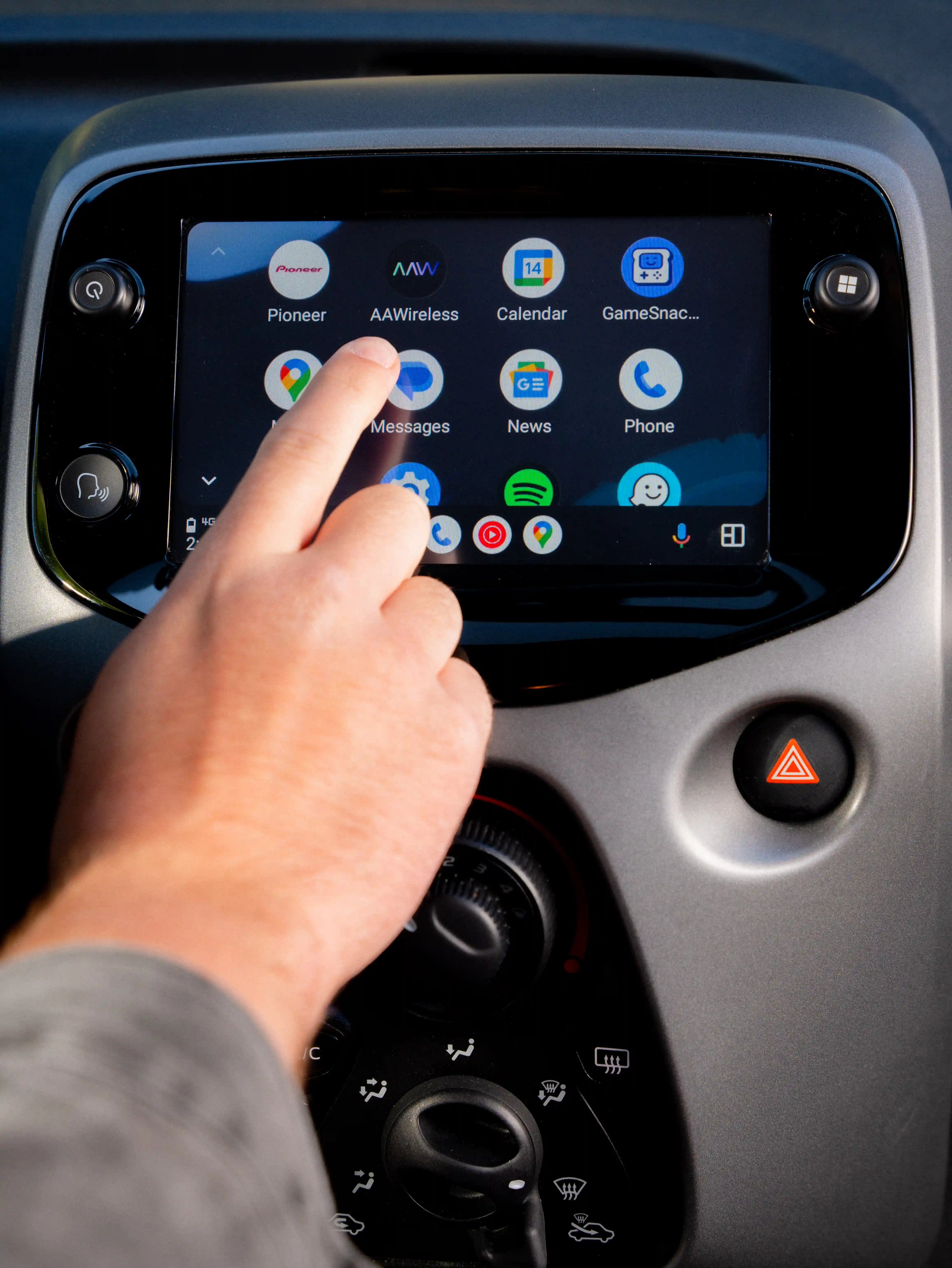 Hand holding an AAWireless dongle in front of a car dashboard.