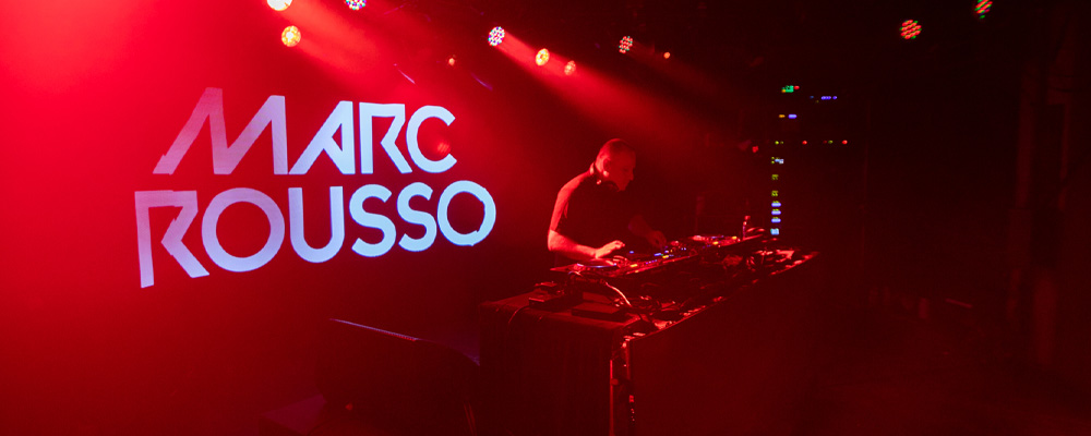DJ Marc Rousso. Marc on stage at large festival with name in lights.