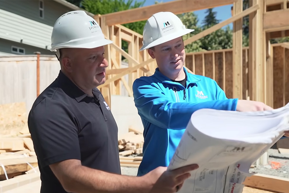 Marc Rousso and architect looking at blueprints on site for a new custom home build for JayMarc Homes.