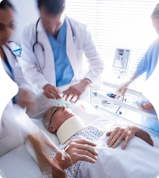 Medical team providing emergency care to an elderly male patient lying on a hospital bed wearing a neck brace and oxygen mask.