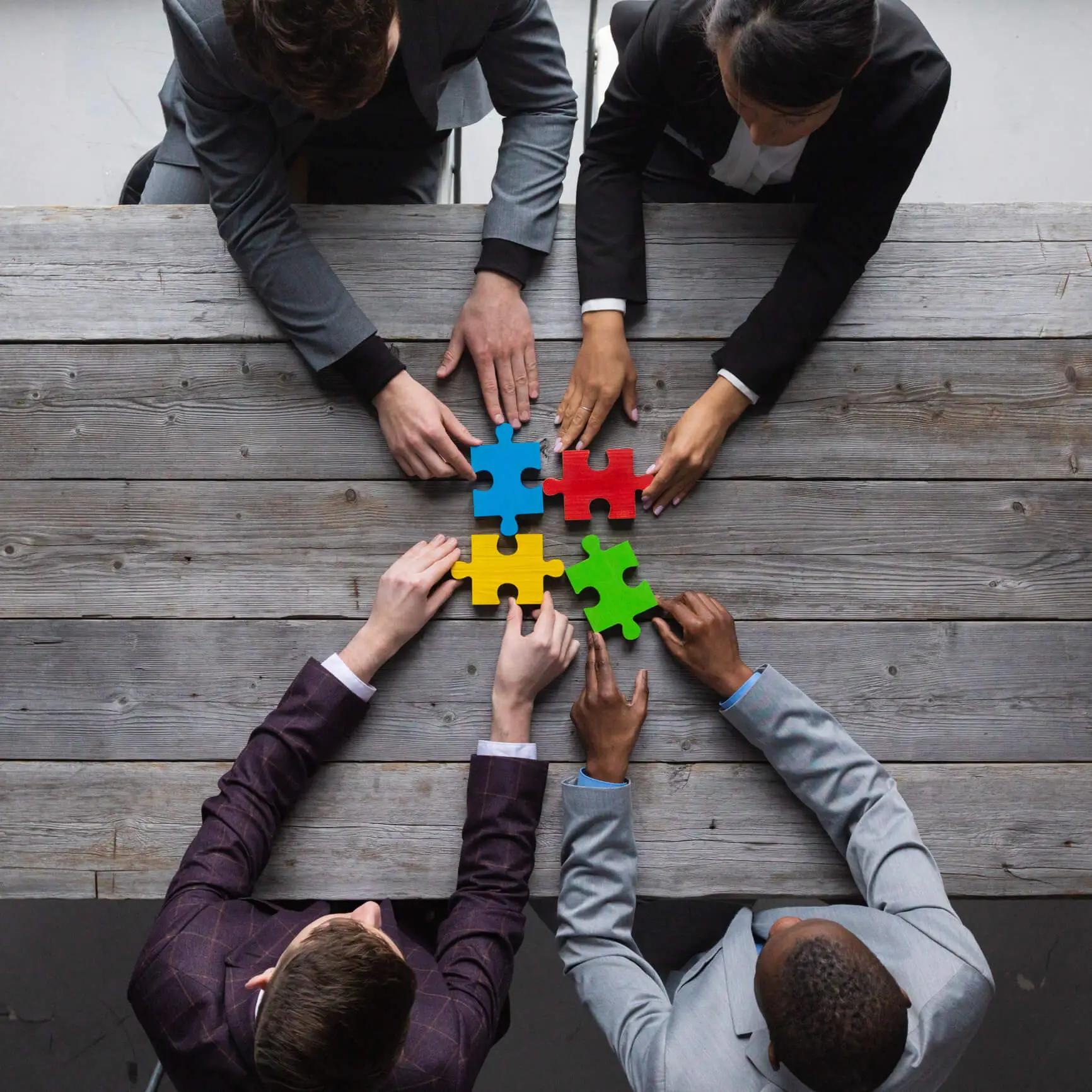 Business people holding a coloured puzzle pieces together