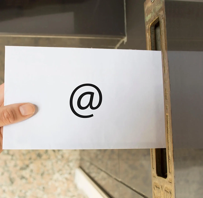 Hand posting a letter with the '@' symbol big in black

