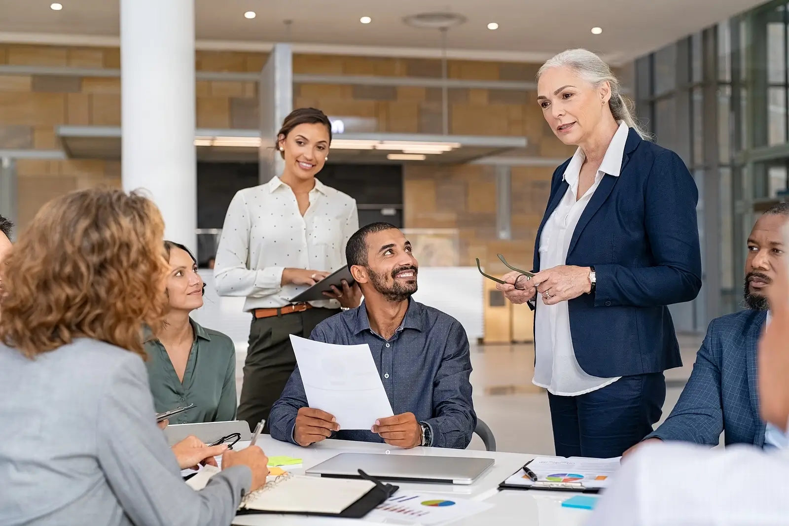 A team of people in the office being lead by a older women CEO