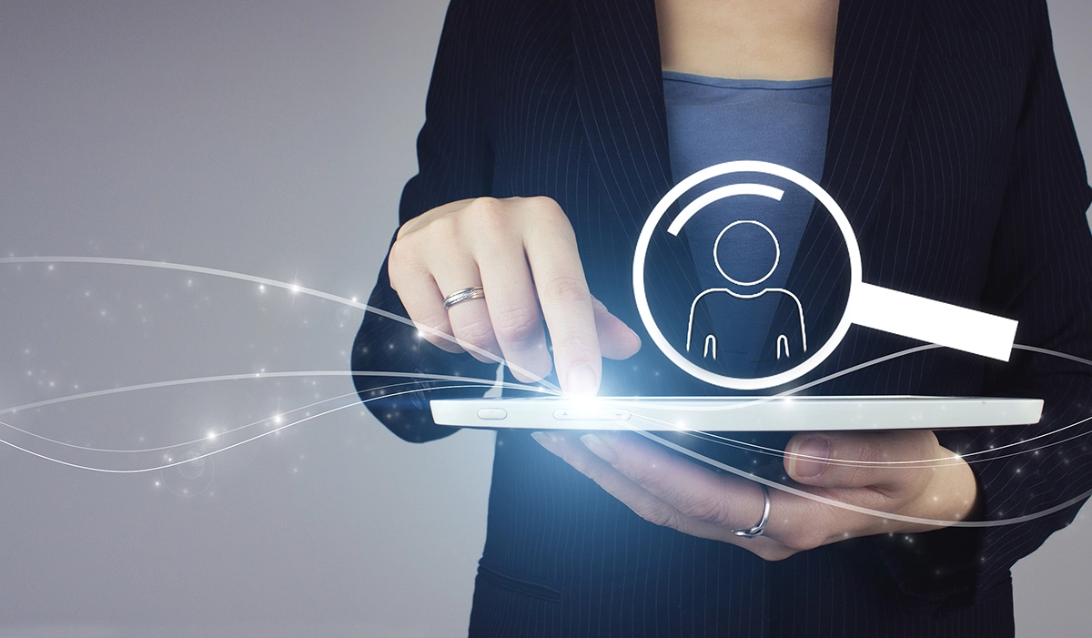 Women holding a tablet with a magnifying glass graphic hover above it