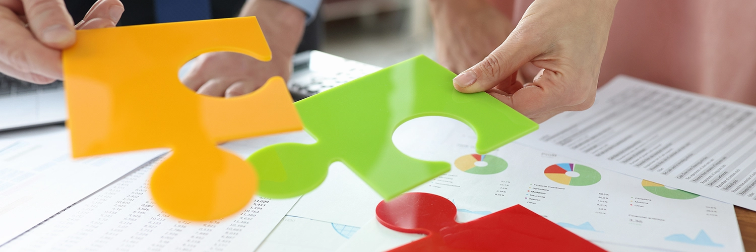 Yellow, green and red puzzle pieces laid out and people trying to piece them together