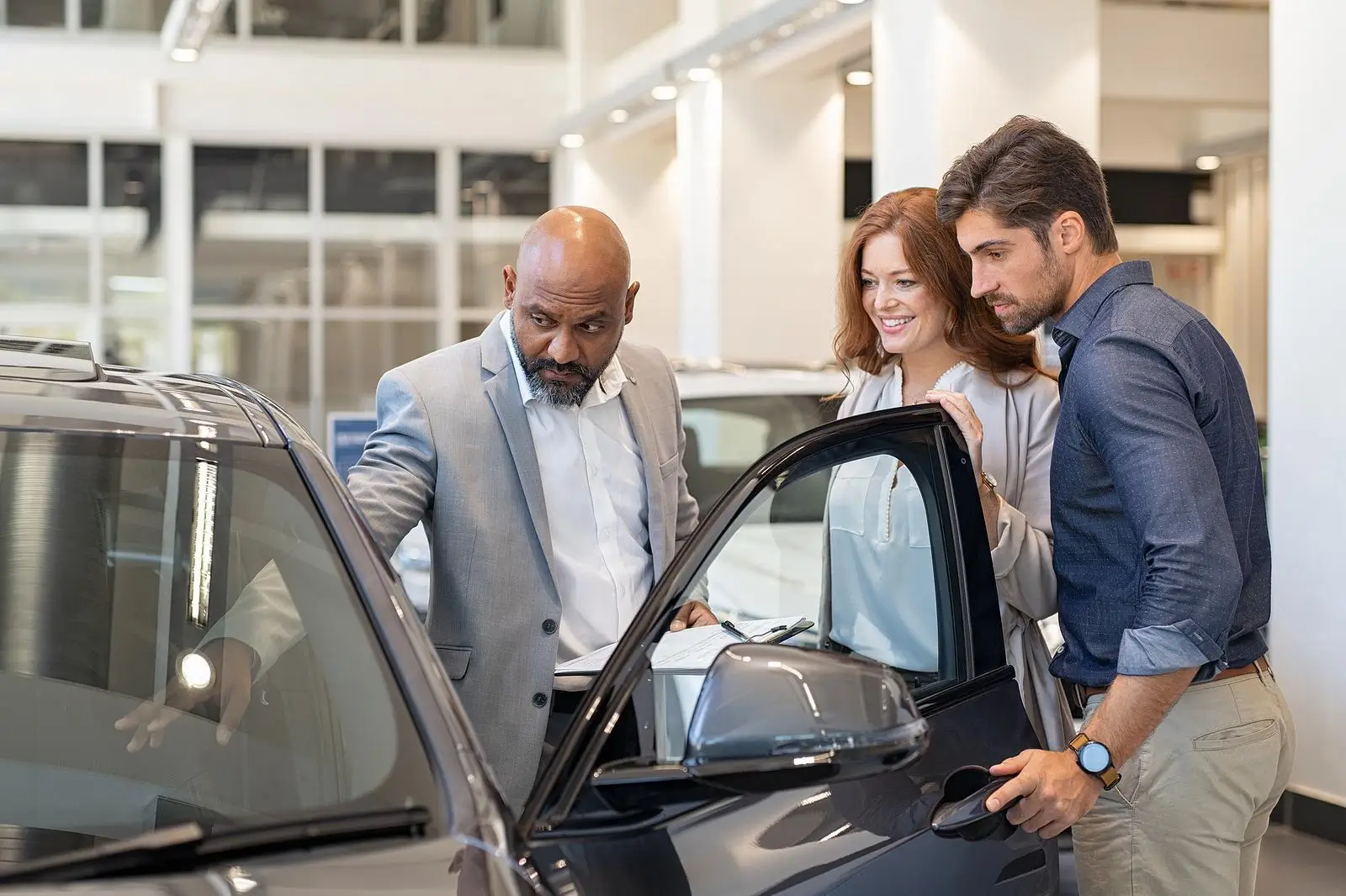 Care Dealership sales men showing couple a new car