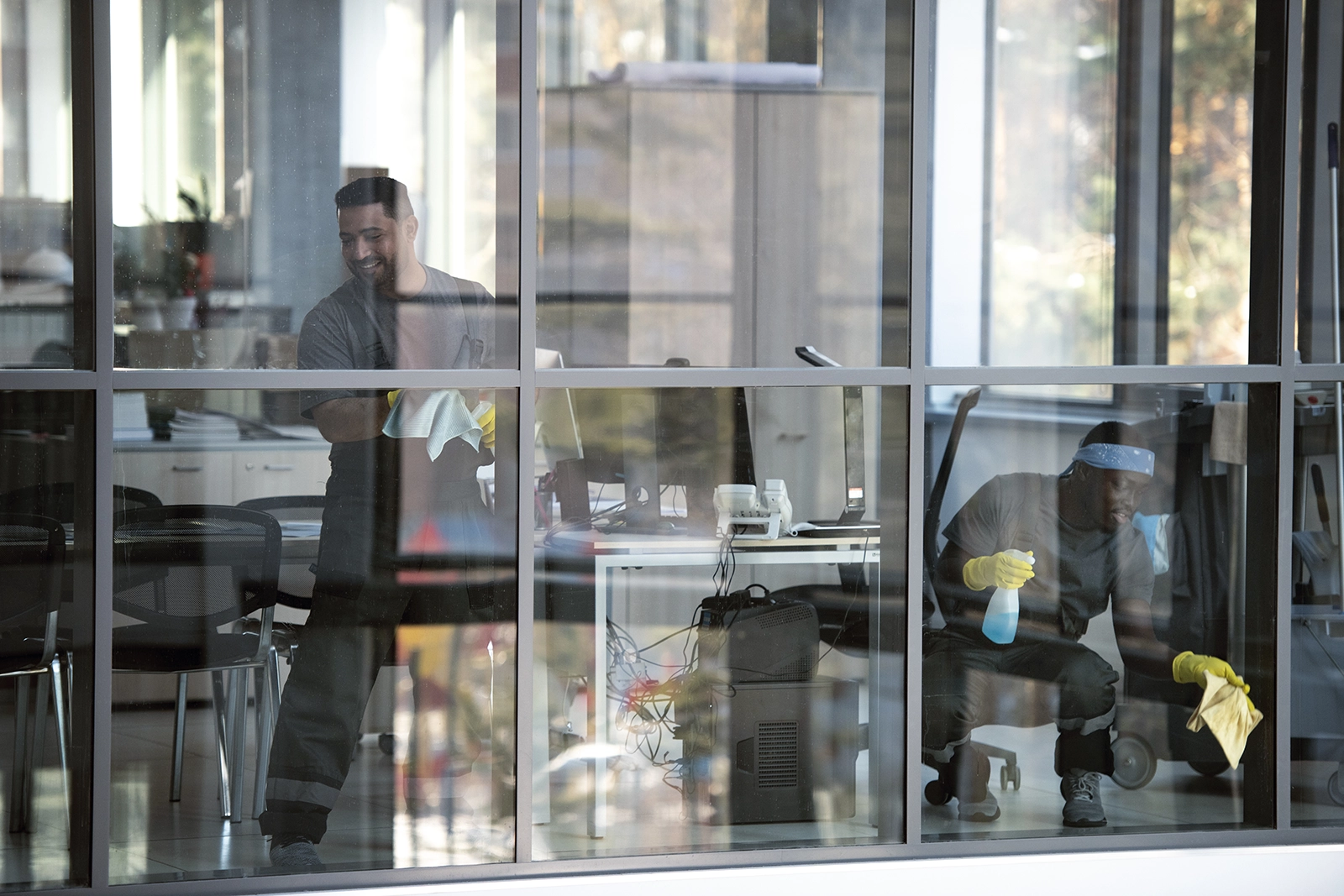 Cleaners in a open plan office cleaning the windows