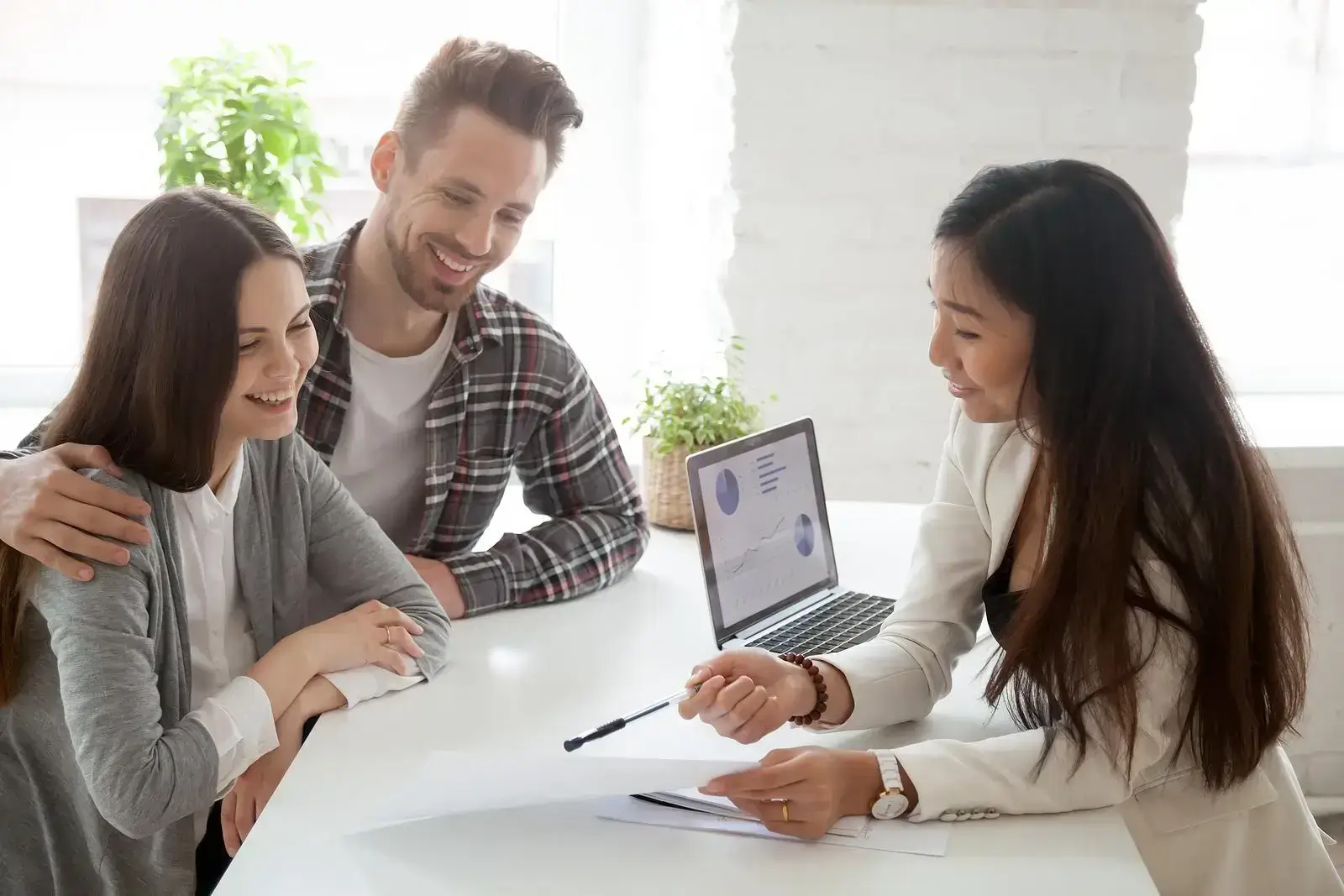 Happy young couple with an asian mortgage broker