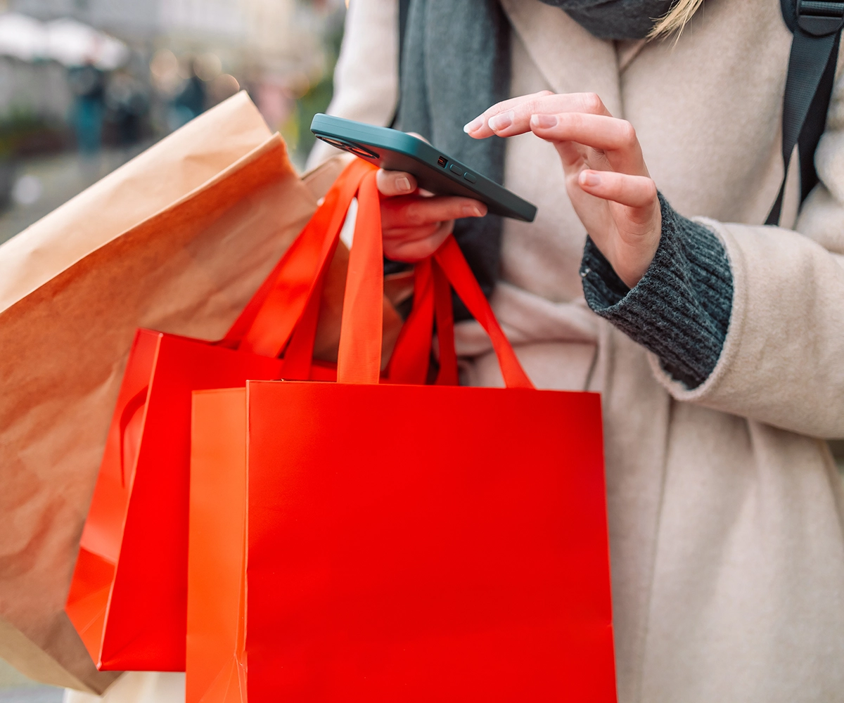 Women looking at her phone while carrying boutique shopping bags