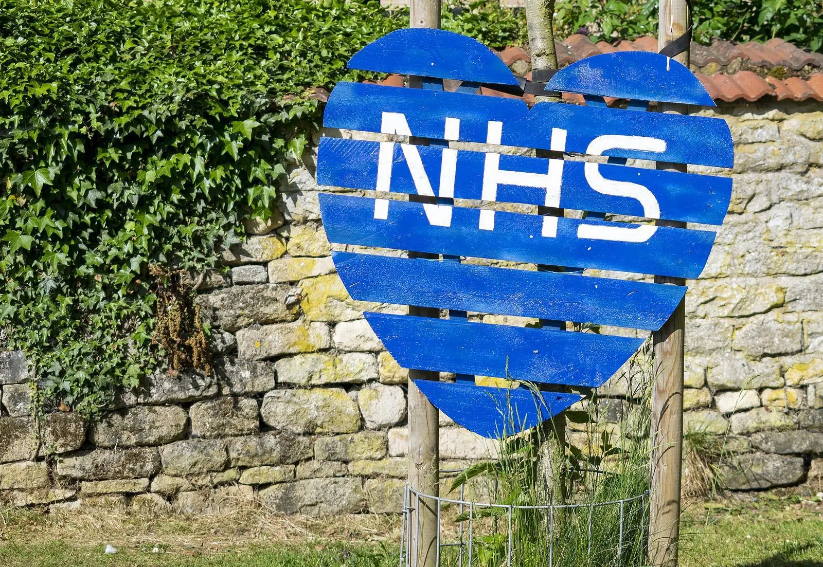 Country lane with a hand made heart shaped sign with the tex - NHS painted on