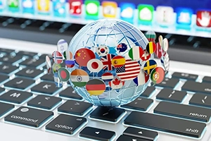 Close up of a transparent globe with flags of countries wrapped round it set on a laptop keyboard