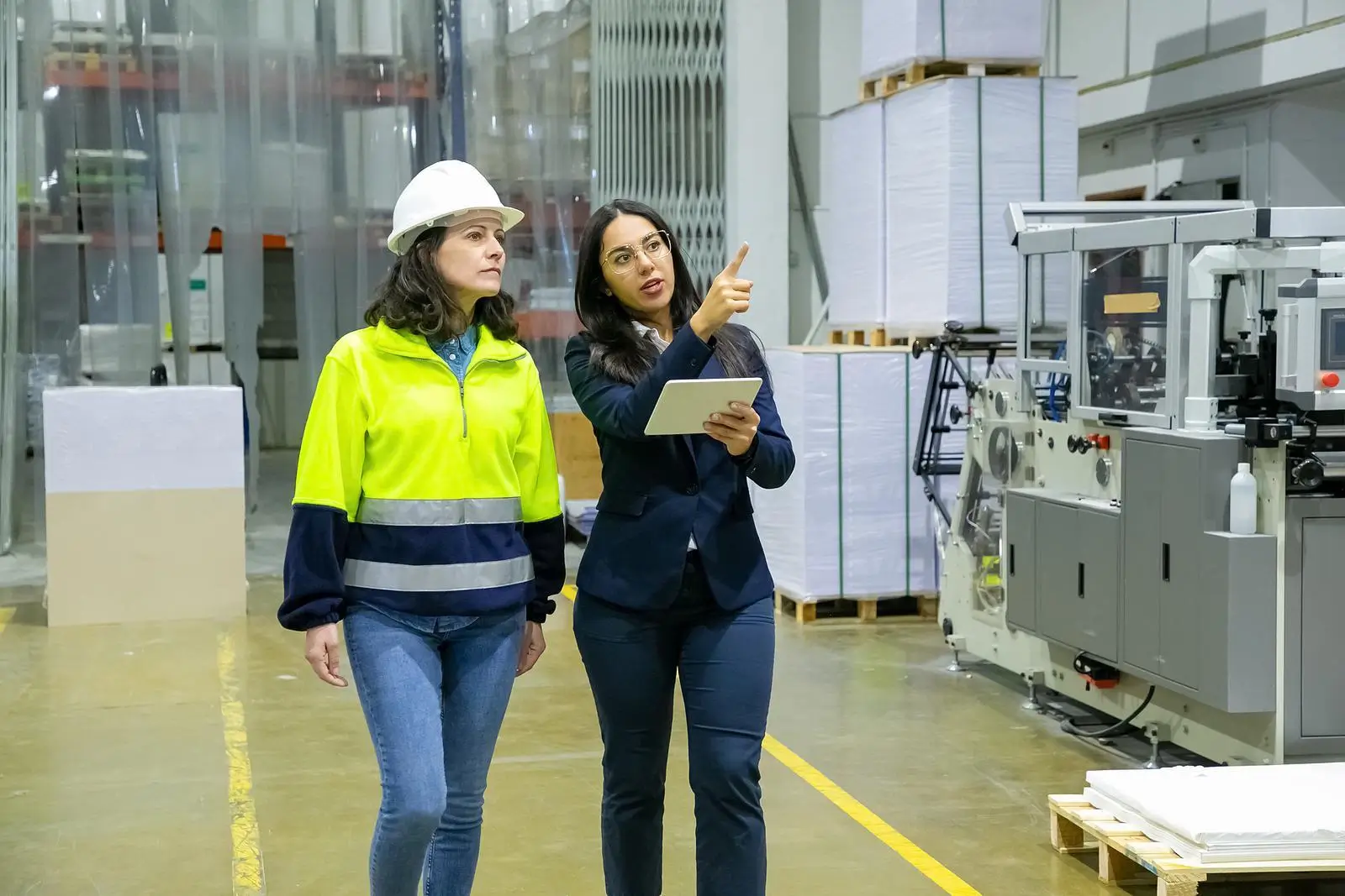 Two women touring the factory floor in high visibility clothing