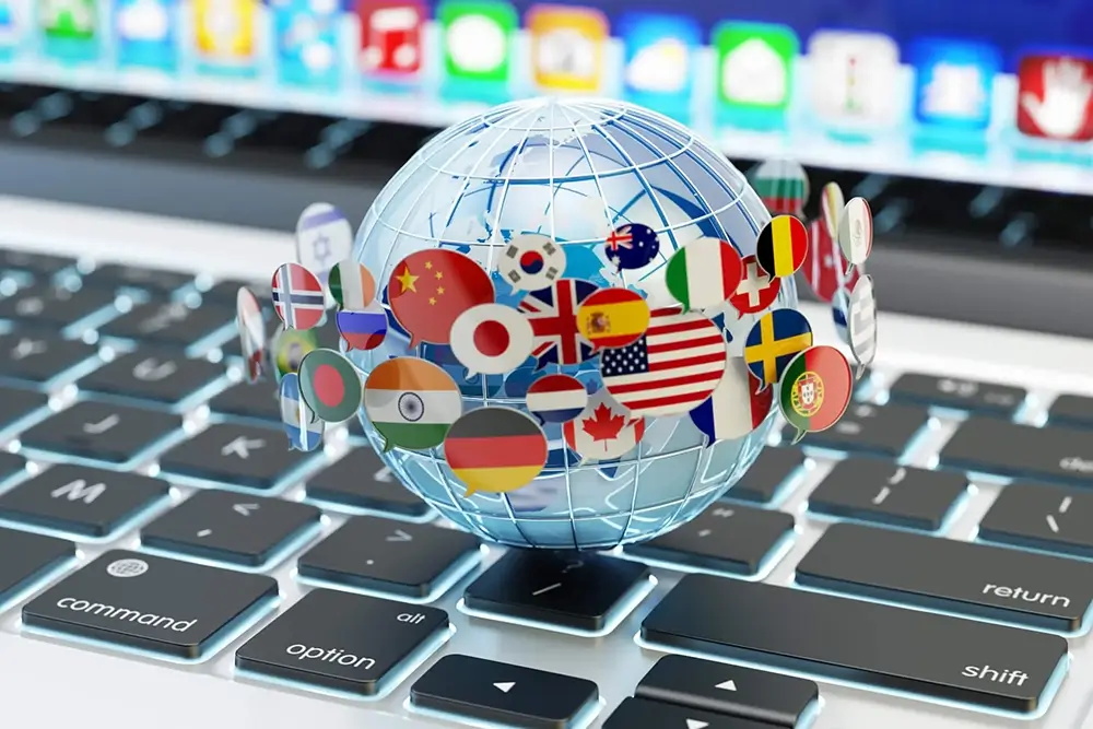 Close up of a transparent globe with flags of countries wrapped round it set on a laptop keyboard