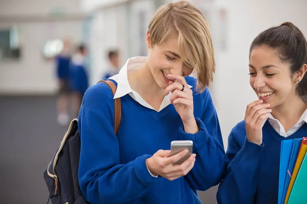 Close up of giggling school kids while looking at there mobile phone