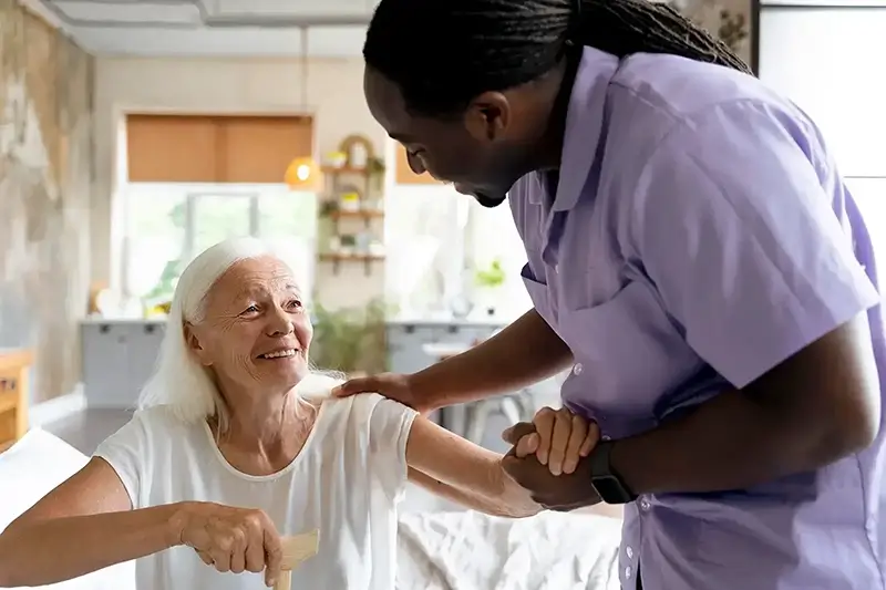 male carer in purple uniform looking after an elderly women