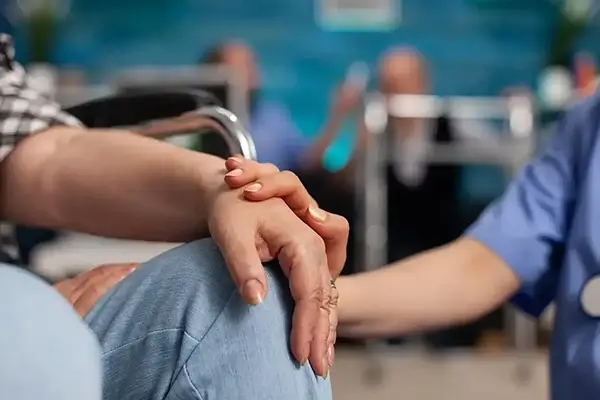 Close-up of a carer holding the hand of a elderly person