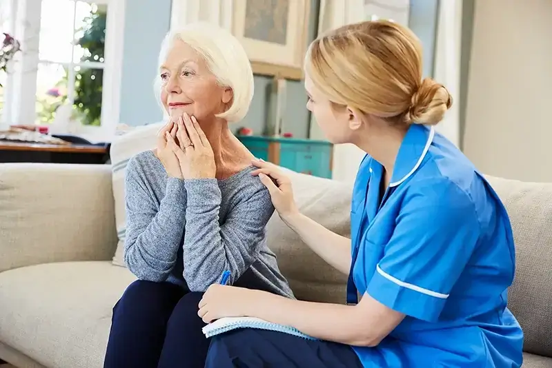 Female carer in blue uniform looking after an elderly women
