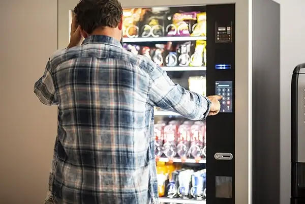 Distant view of the of a man deciding what to purchase from the vending machine