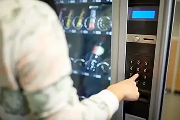 Close up of the of a man using a vending machine button panel to purchase a snack