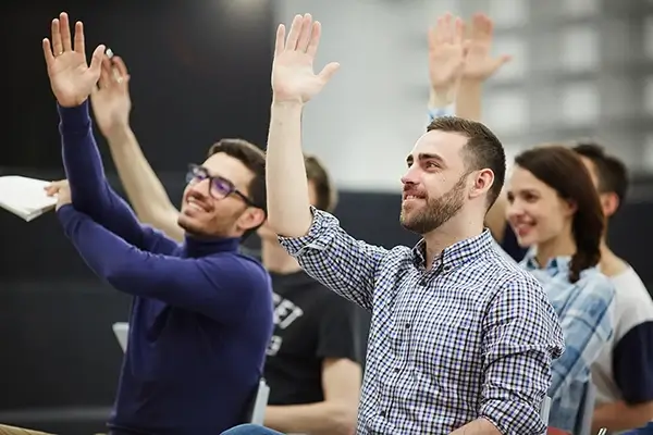 Group of young people with there hands up in a meeting room