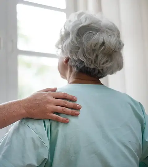 Close -up of a Smiling carer with her hand on a elderly women's back
