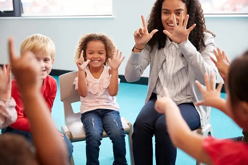 Classroom of young primary school children learning hand signs with numbers