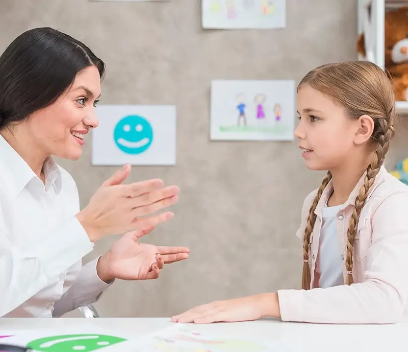 Young women teaching a little girl to speak