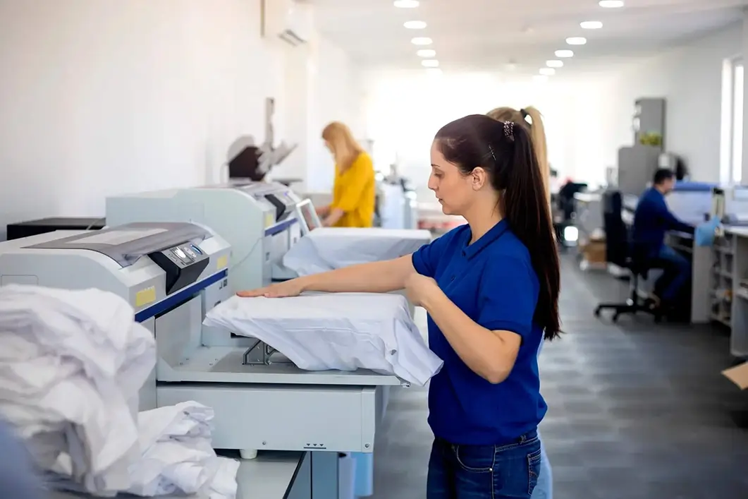 Women using a t-shirt printing machine in a factory