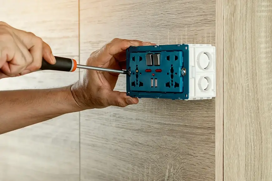 Close-up of an electrician installing a plug socket panel
