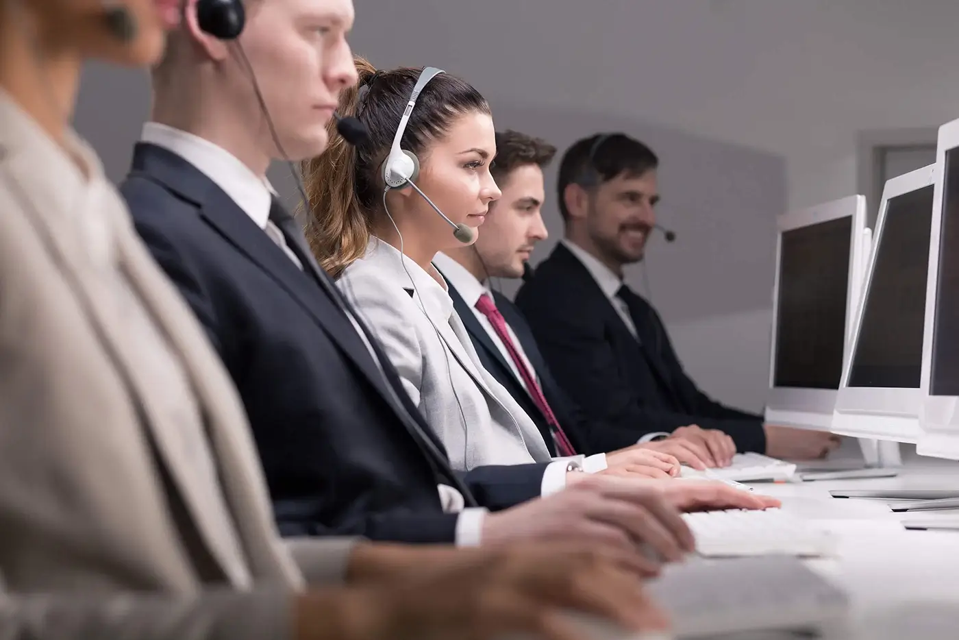 A row of customer service employees in a business setting wearing headsets