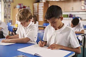 Close up of 2 primary school boys working in a classroom setting
