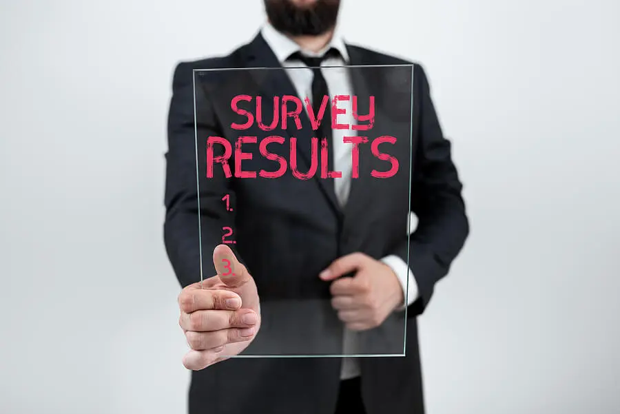 Man holding a sign saying survey results