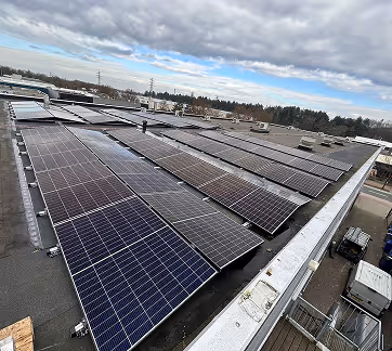 Zonnepanelen array op het dak van een industrieel gebouw onder bewolkte lucht.