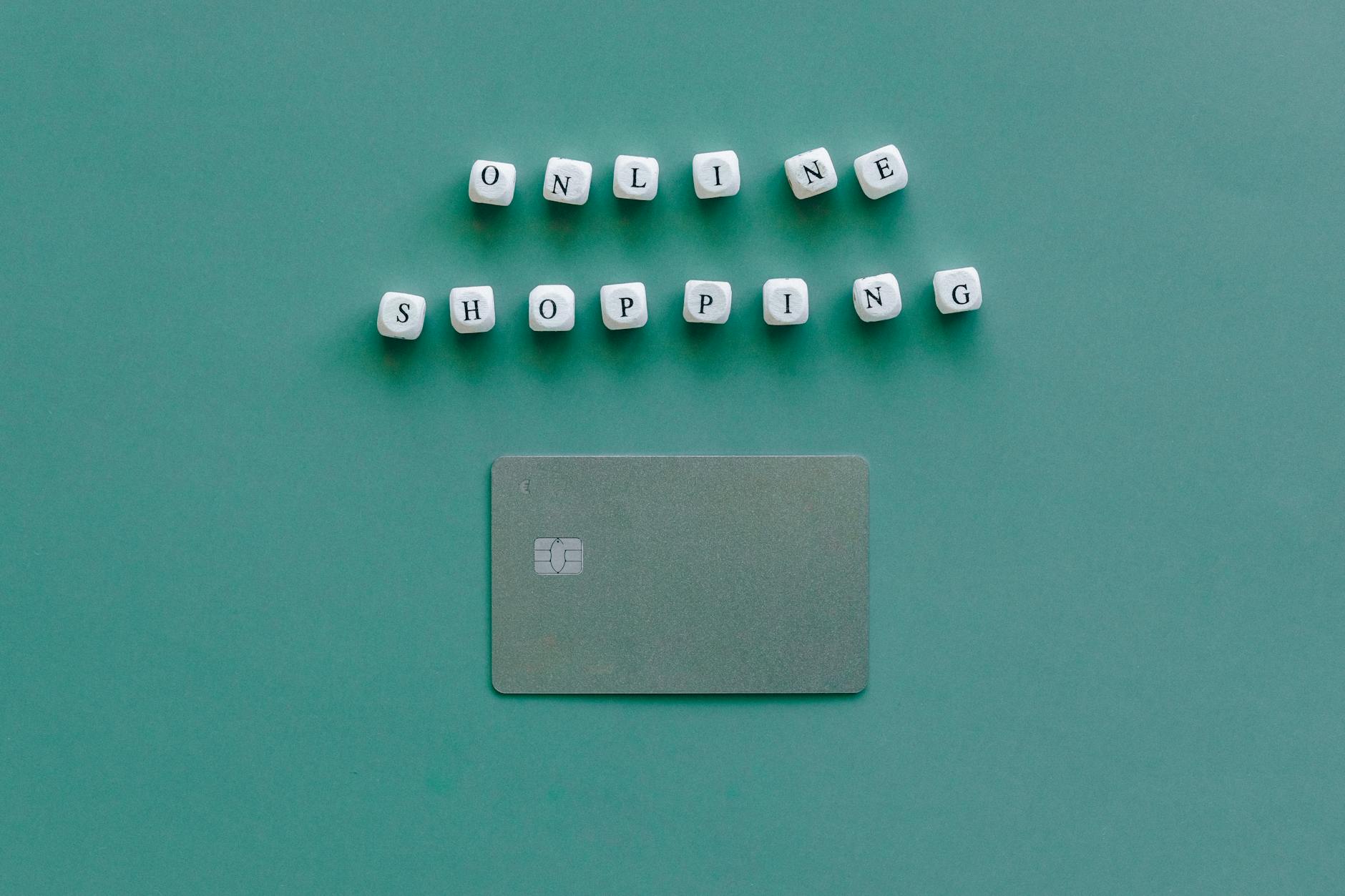 Flat lay of credit card and 'Online Shopping' text on green background, symbolizing ecommerce.