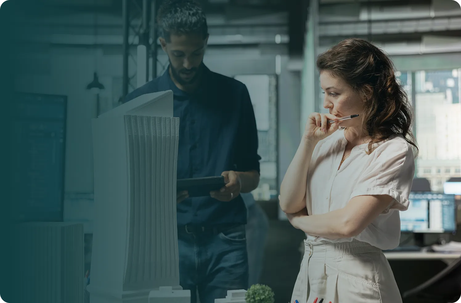 Two architects reviewing a scale model of a modern building in an office.
