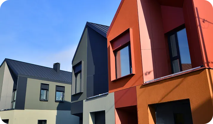 Modern row of colorful townhouses in gray, black, and red under a clear blue sky.