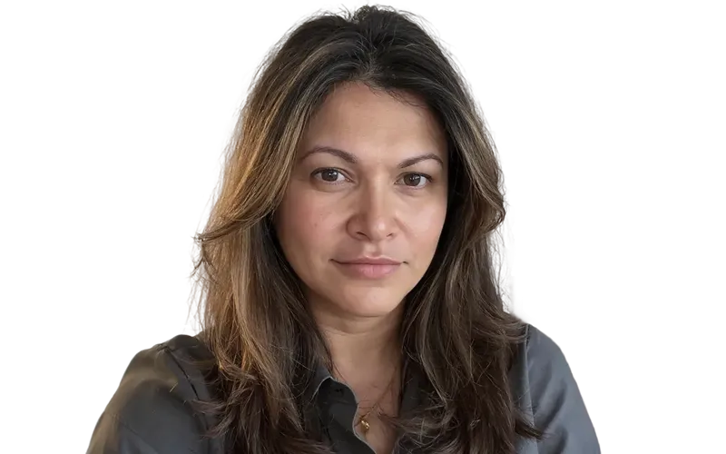 Woman with long brown hair wearing a dark gray button-up shirt, looking at the camera with a neutral expression.