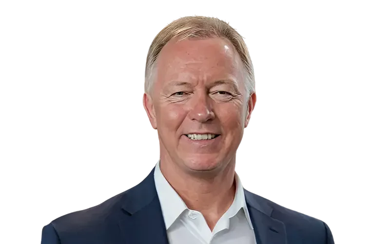 Smiling middle-aged man with short gray hair wearing a white shirt and navy blue blazer.