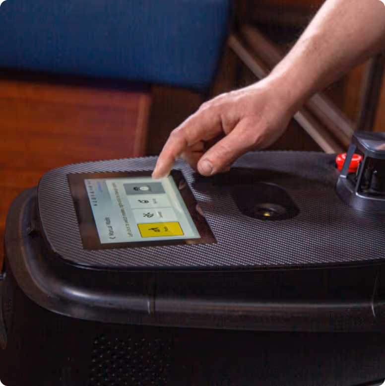 Hand interacting with touchscreen control panel on a black robotic device.