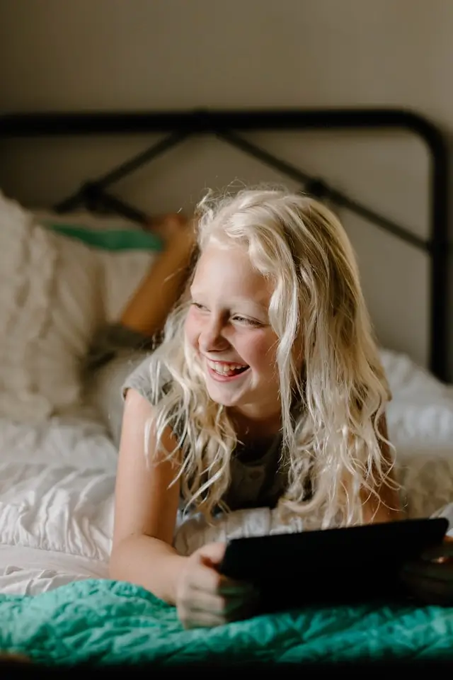 Smiling young girl being swung by two adults holding her hands indoors.
