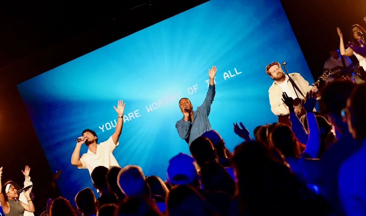 VOUS Worship leading on stage with hands raised in front of the crowd