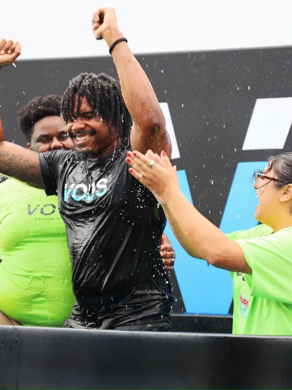 A woman celebrates as she comes up from the water at a VOUS baptism