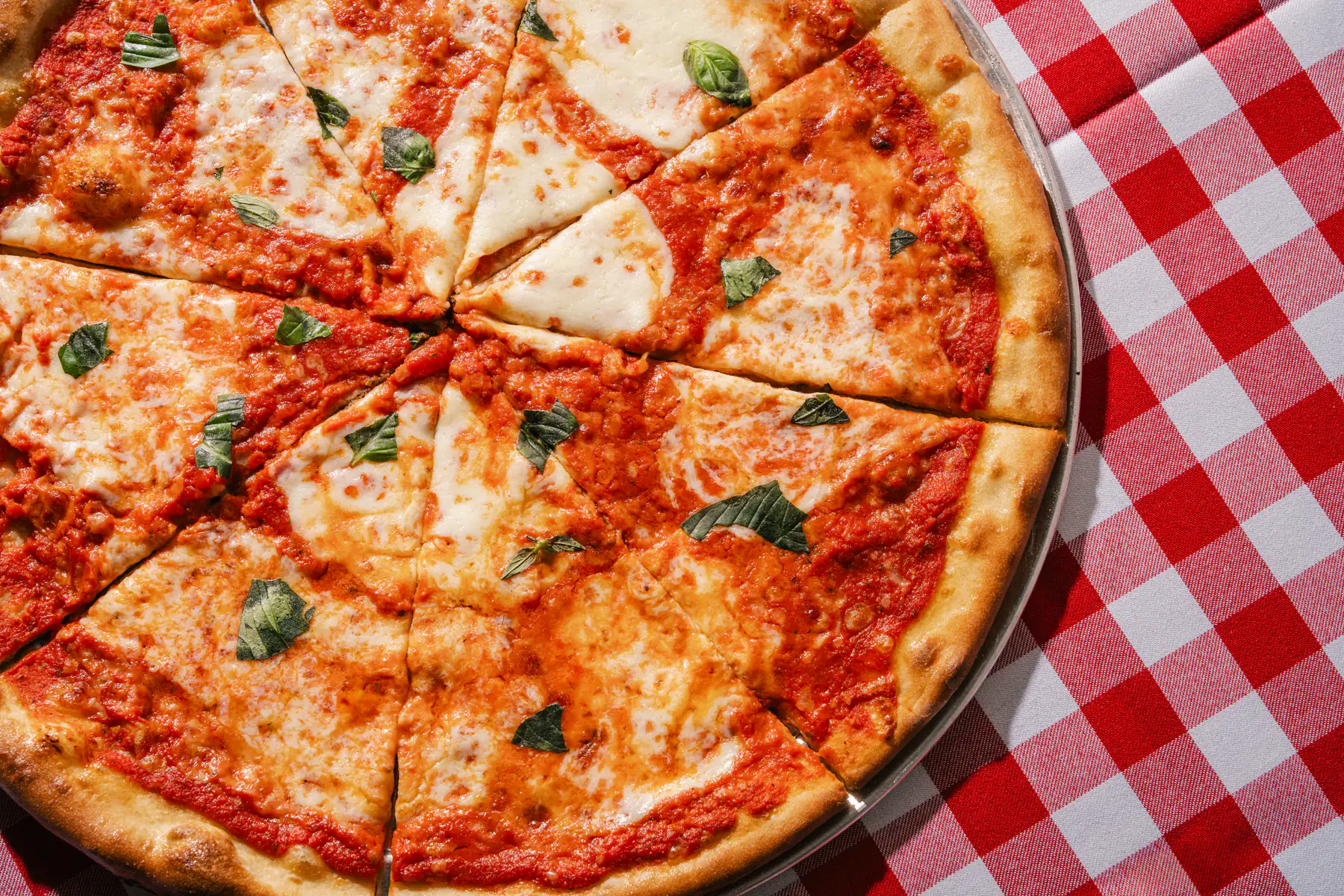 Close-up of a sliced margherita pizza with fresh basil at Frankie's Pizza Parlor.