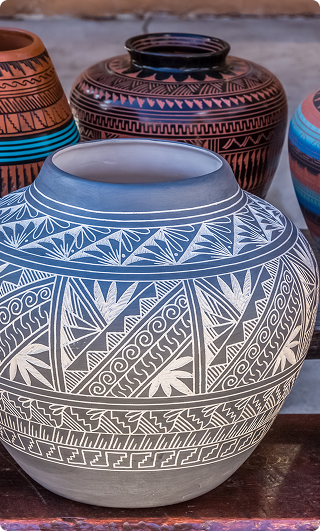 Decorative clay pots with intricate geometric and floral patterns in black, white, brown, and turquoise colors.