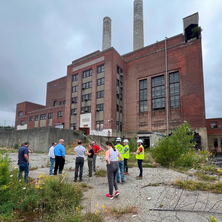 Brick power plant building with people gathered outside.