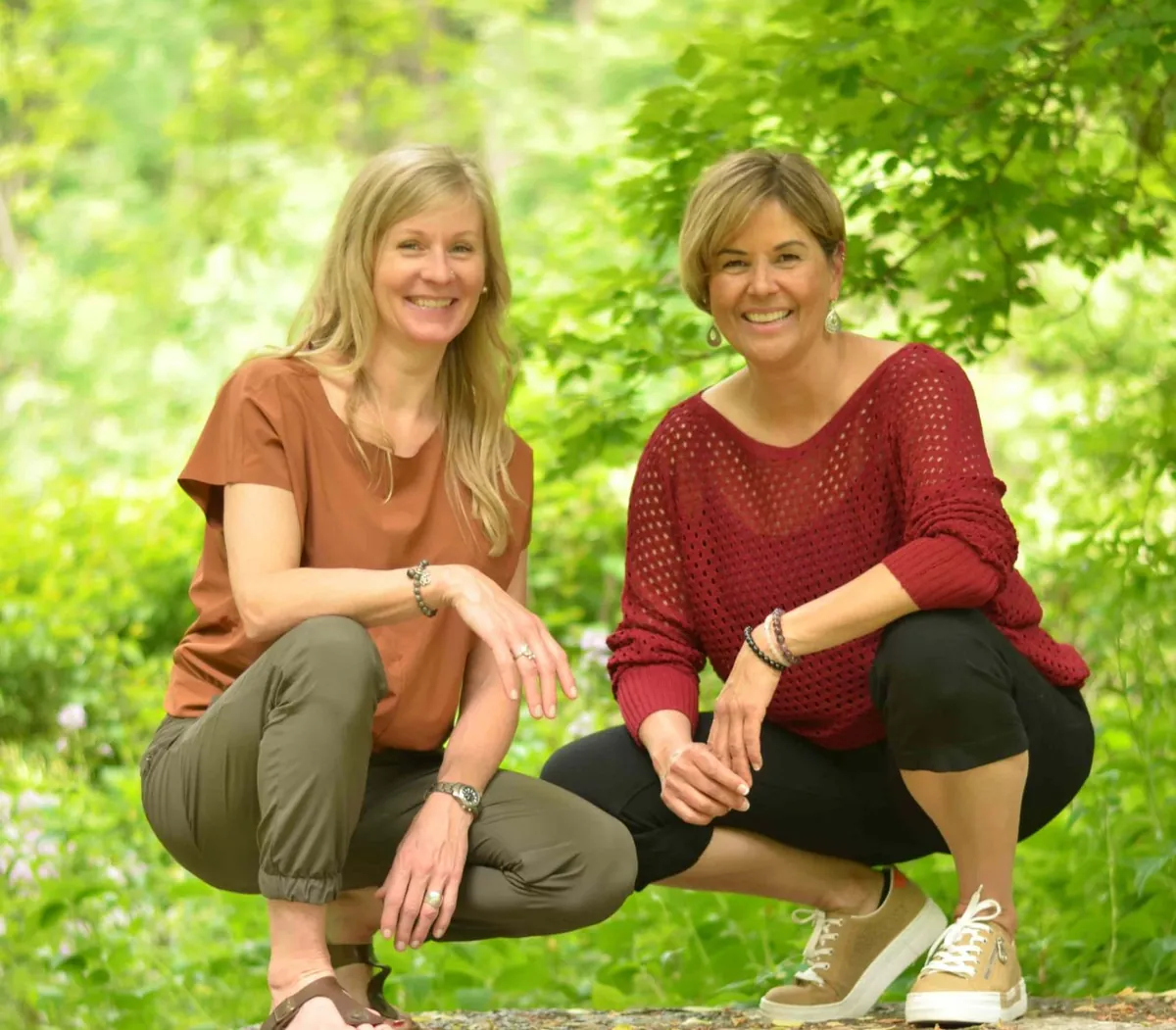 Carrie Meyer and Nicole Ablack Ramkay smiling together outdoors in a green forest